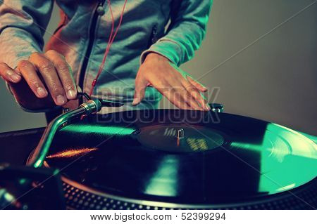 Dj hands on equipment deck and mixer with vinyl record at party