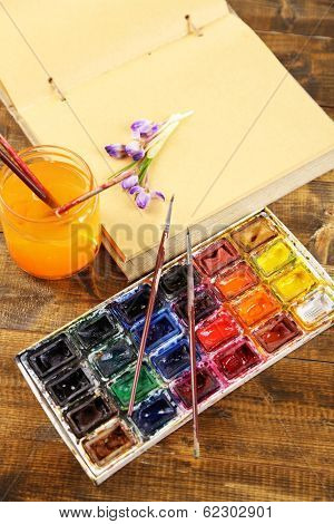 Composition with colorful watercolors, brushes and sketcher on wooden background 