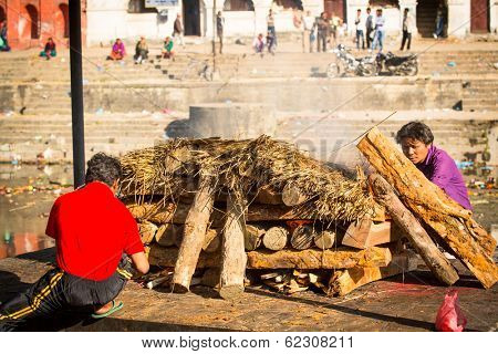KATHMANDU, NEPAL - DEC 3, 2013: Unidentified local people during the cremation ceremony along the holy Bagmati River in Bhasmeshvar Ghat at Pashupatinath temple in Kathmandu.