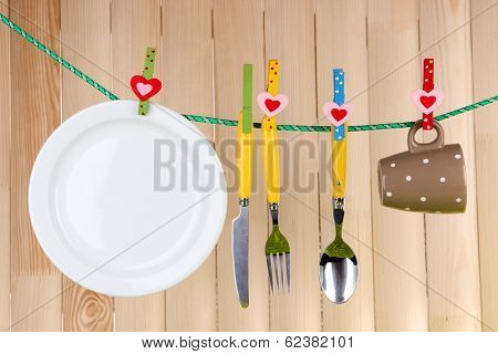 Tableware dried on rope on wooden background