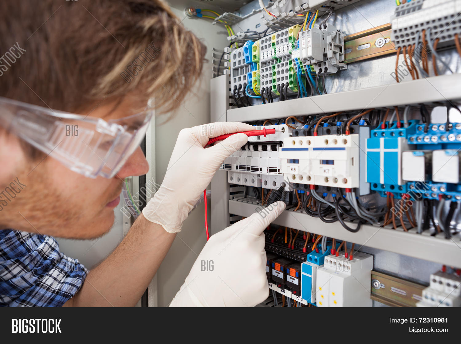 Electrical Engineer Examining Fusebox With Multimeter Probe