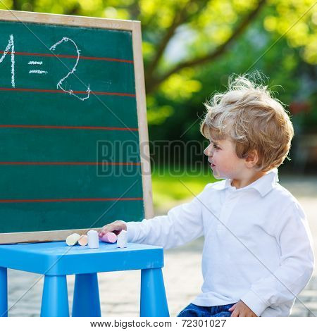Little Boy At Blackboard Practicing Mathematics