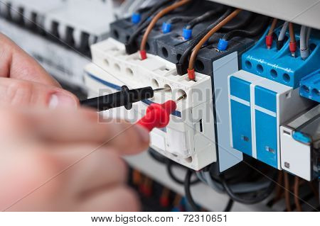 Electrician Examining Fusebox With Multimeter Probe