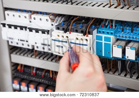 Electrician Examining Fusebox With Screwdriver
