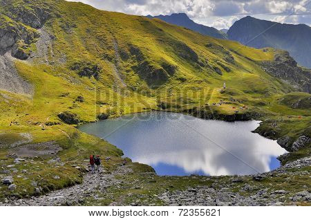 Tourists hiking and camping near mountain lake