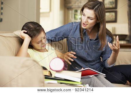 Mother Becoming Frustrated With Daughter Whilst Doing Homework Sitting On Sofa At Home