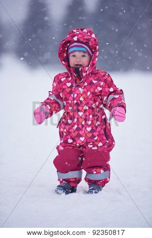 happy family on winter vacation, mom and cute little girl have fun and slide while snow falkes falling