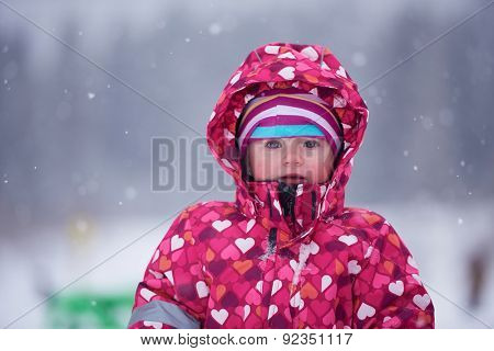 happy family on winter vacation, mom and cute little girl have fun and slide while snow falkes falling