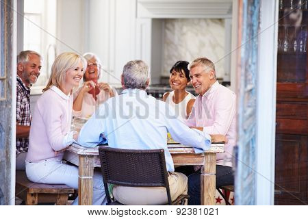 Group Of Mature Friends Enjoying Meal At Home Together