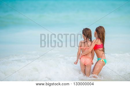 Adorable little girls have fun on white beach during vacation