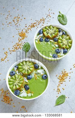 breakfast green smoothie bowl topped with kiwi, blueberry, coconutflake and bee pollen