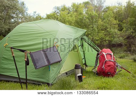 Camping in the woods with a backpack and a tent on the banks of the river in the summer.