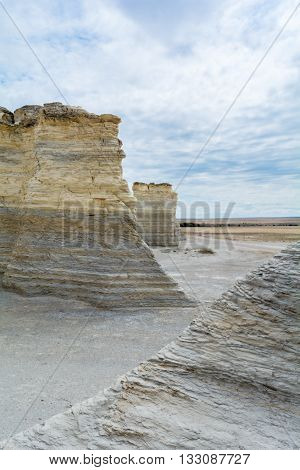 A limestone bluff sits on a bed of grey gravel in a flat pairie.