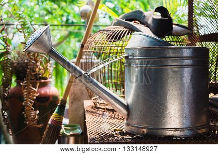 Watering can on rusty table bird cage background