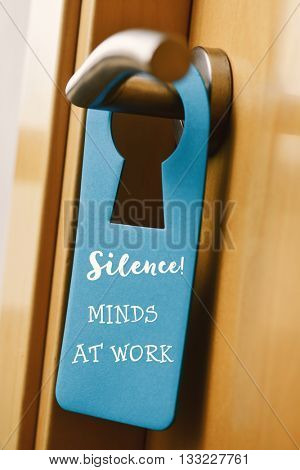 closeup of a blue door hanger with the text do not disturb hanging on the handle of a pinewood door
