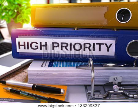 High Priority - Blue Office Folder on Background of Working Table with Stationery and Laptop. High Priority Business Concept on Blurred Background. High Priority Toned Image. 3D.