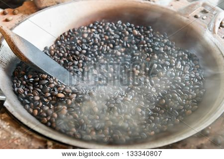 Traditional roasting dark coffee beans in pan.