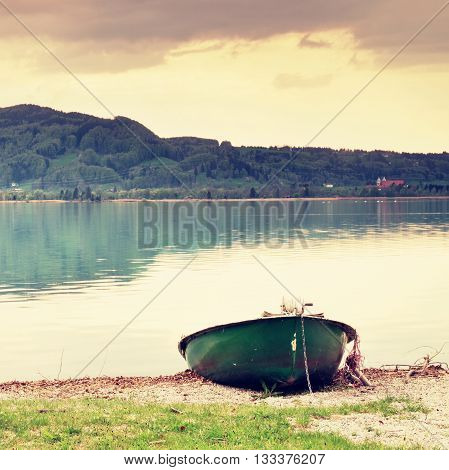 Abandoned Fishing Paddle Boat On Bank. Morning Alps Lake