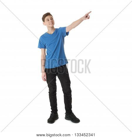 Cute teenager boy in blue T-shirt standing and poinitng up side over white isolated background full body