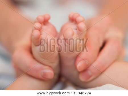 Matka jemně v ruce držet nohy Baby