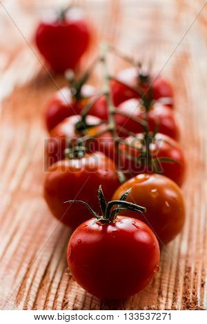 Small cherry tomatoes on the wooden background. Closeup, selective focus.