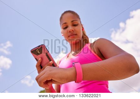 Young people doing sport activities woman runner jogging programming fit watch and synchronizing data with mobile phone wirelessly