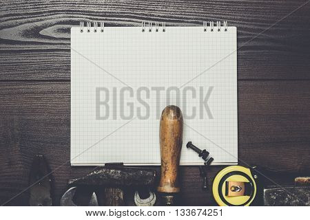construction tools and blank notepad on wooden background
