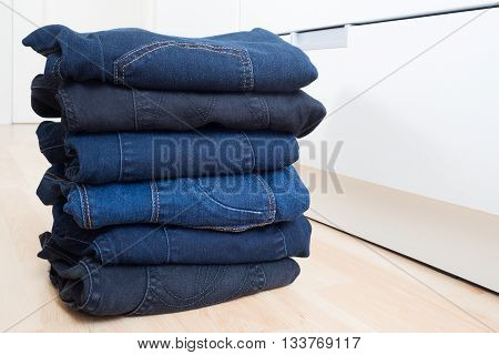 Blue and black jeans stacked on wood floor
