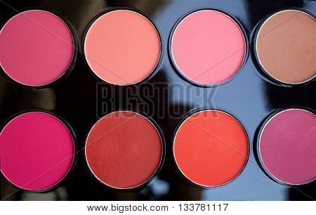Colorful blush set on black background. Dry textured palette of professional cosmetics. Artistic retouching.