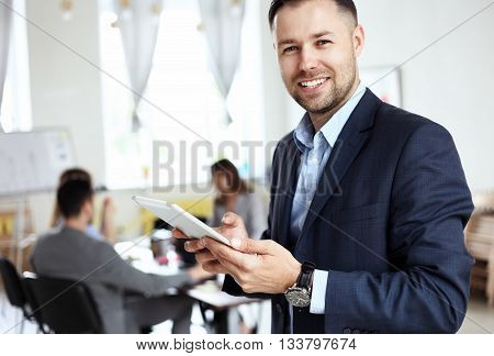 Handsome smiling confident businessman portrait in office