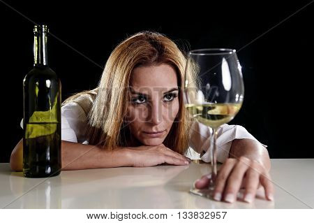 drunk blond woman alone in wasted depressed face expression looking thoughtful to white wine glass isolated on black background in alcohol abuse and alcoholic housewife concept