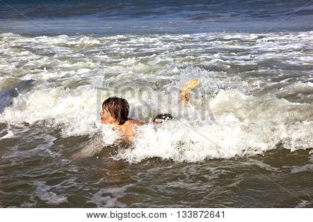 Young Boy Is Body Surfing In The Waves Of The Ocean