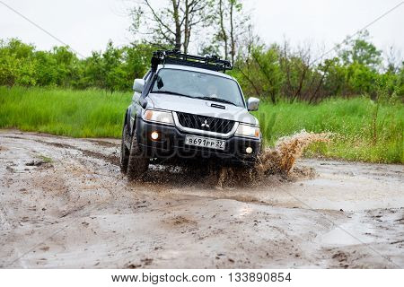 NIKOLAEVKA RUSSIA - JUNE 11 2016: Mitsubishi Pajero moving by water in the rain making lots of splashes