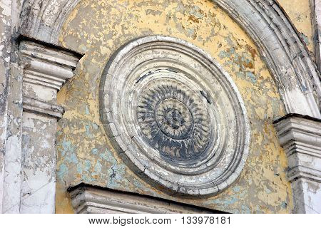 Fragment of wall of church building - beautiful old gypsum plaster rosace in classical style on the wall