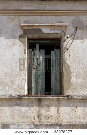 old ruined destroyed window without frame in old building is chock-full of boards