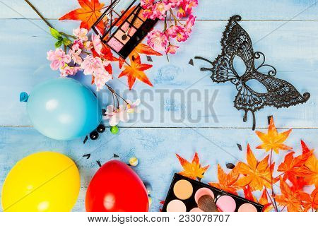 Flat Lay Top Veiw Of Mask Party Preparation Accessories. Cosmetics And Brushes On Blue Wooden Backgr