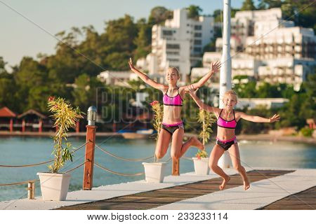 Happy Little Girls On The Pier Jumping