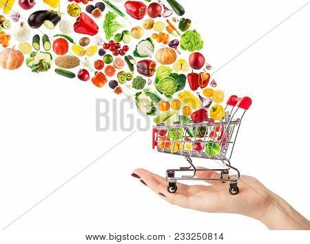 Female Hand Holding Grocery Cart With Vegetables And Fruits Falling In It Isolated On White. Healthy