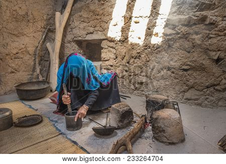 Al Hamra, Oman, March, 24th, 2018: Omani Woman In Traditional Kitchen Roasting Coffee Beans