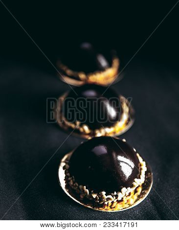 Small Chocolate Cakes On A Black Background. Brownie A
