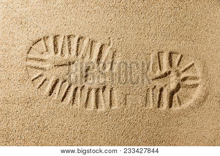 Stamping Left Foot With Boot And Footprint On Sand Of Beach From Top View