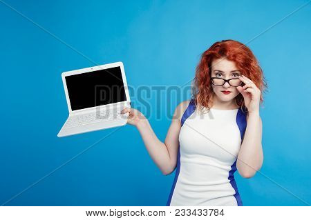 Beautiful Red-haired Girl Holding A Laptop Isolate On A Blue Background