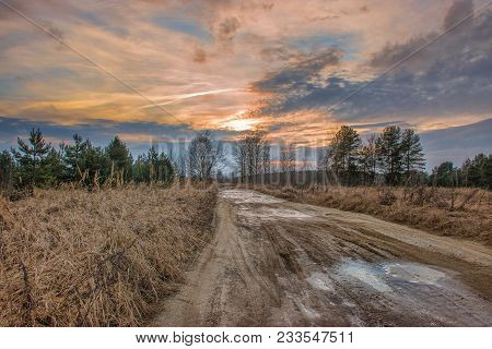 Orange Autumn Sunset, Frozen Ground Road With Puddles Covered With Ice