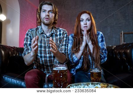 Young Couple Cheering For A Sport Team Watching Sports On Tv. They Are Screaming And Gesturing For A
