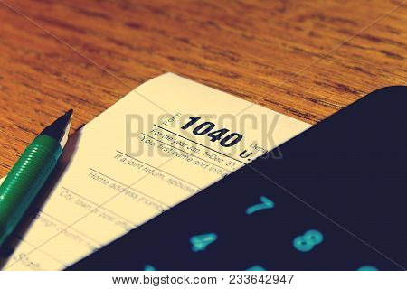Tax Day. The Tax Form 1040, Green Pen And Black Smartphone With Calculator Is On A Wooden Table.
