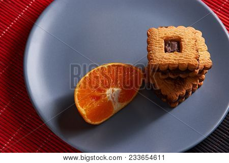 Chocolate Chip Cookies And Orange On Gray Plate And On Red With Black Table