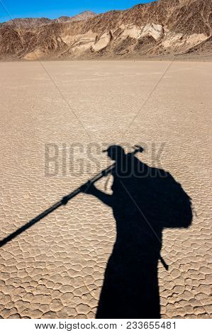 The Shadow Of A Photographer Walking Through The Desert