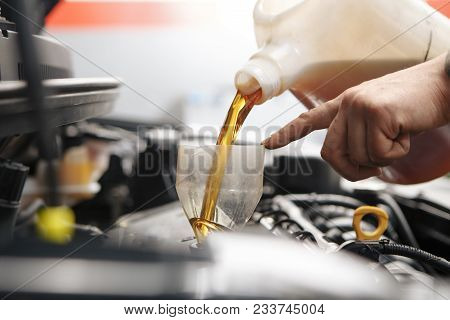 Car Mechanic Replacing And Pouring Fresh Oil Into Engine At Maintenance Repair Service