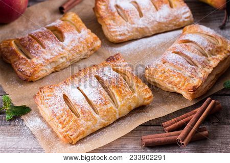 Puff Pastry With Apples And Powdered Sugar On A Wooden Table