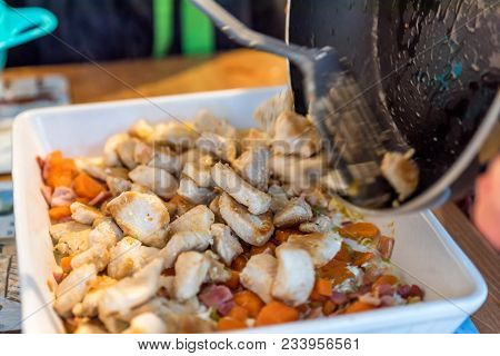 Closeup View Pieces Of Fried Chicken Breast Thrown From Pan To White Ceramic Baking Tray With Carrot
